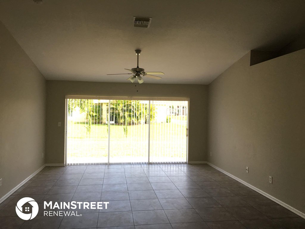 an empty living room with a ceiling fan and sliding glass doors