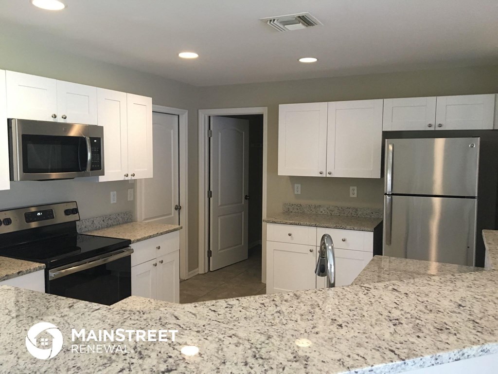 a white kitchen with granite counter tops and stainless steel appliances