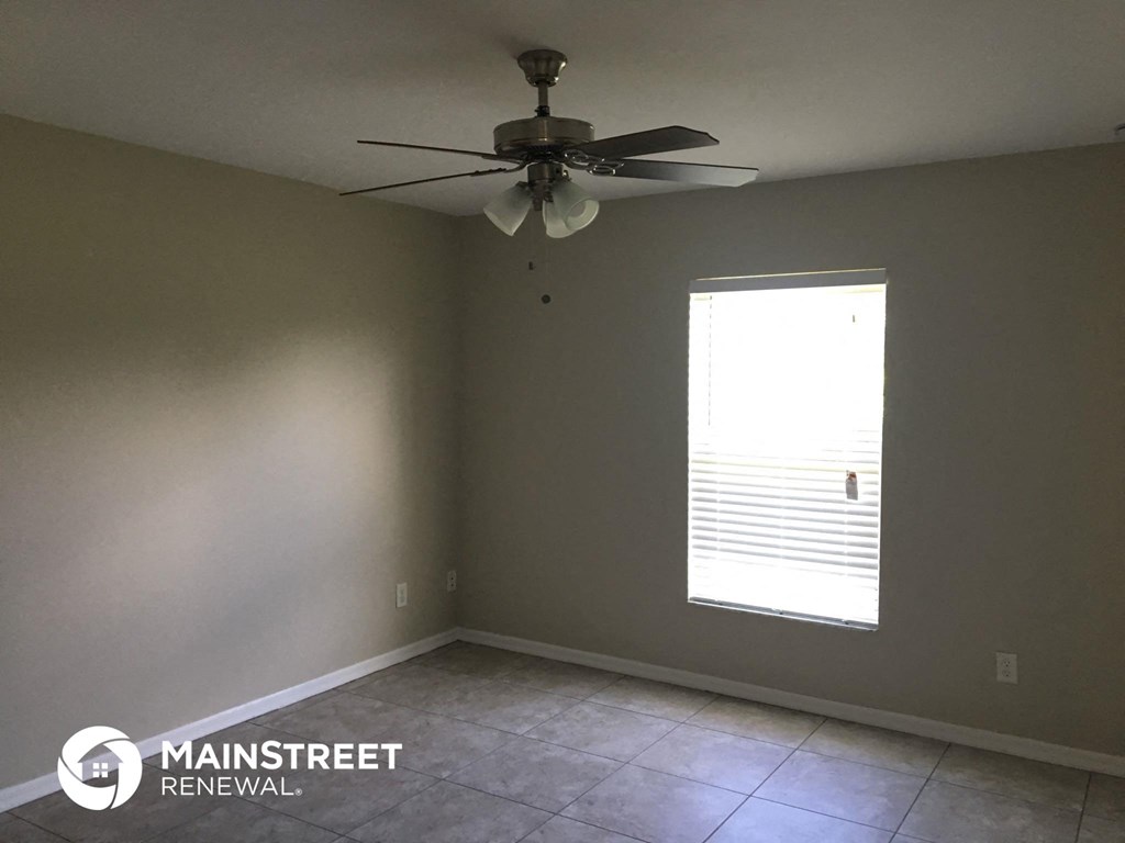 an empty room with a ceiling fan and a window
