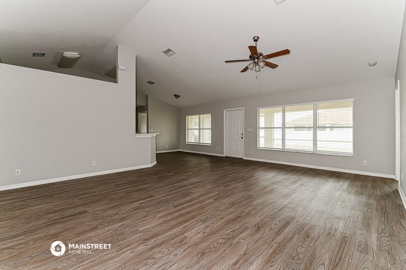 the living room of an empty house with a ceiling fan