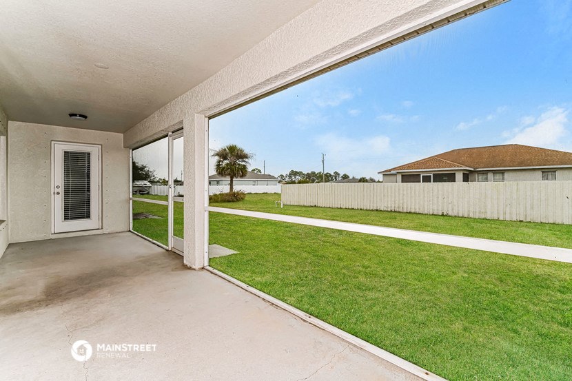 a covered patio with a view of a yard and a house