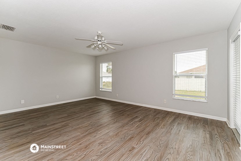 the living room with wood flooring and a ceiling fan