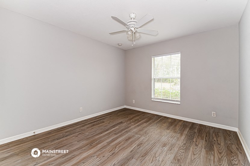 the living room of a rental home with wood flooring and a ceiling fan
