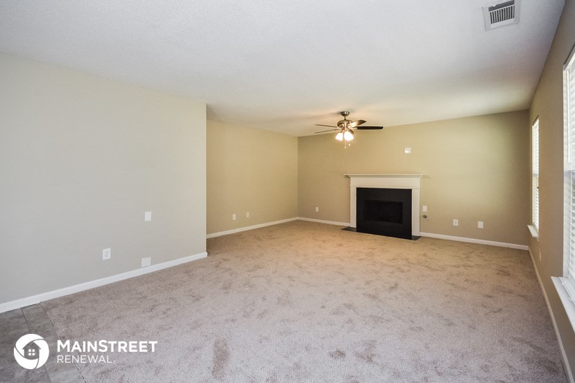 an empty living room with a ceiling fan and a fireplace