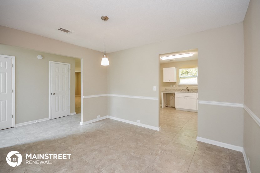 an empty living room and kitchen with a white door