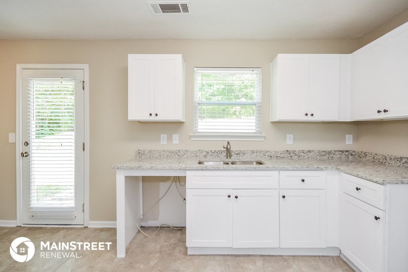 a kitchen with white cabinets and a counter top and a sink