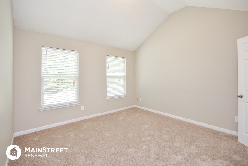 the spacious upstairs bedroom with carpeting and two windows