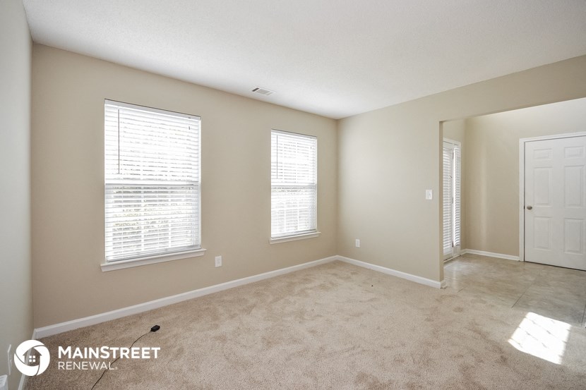 a spacious living room with a carpeted floor and a white door