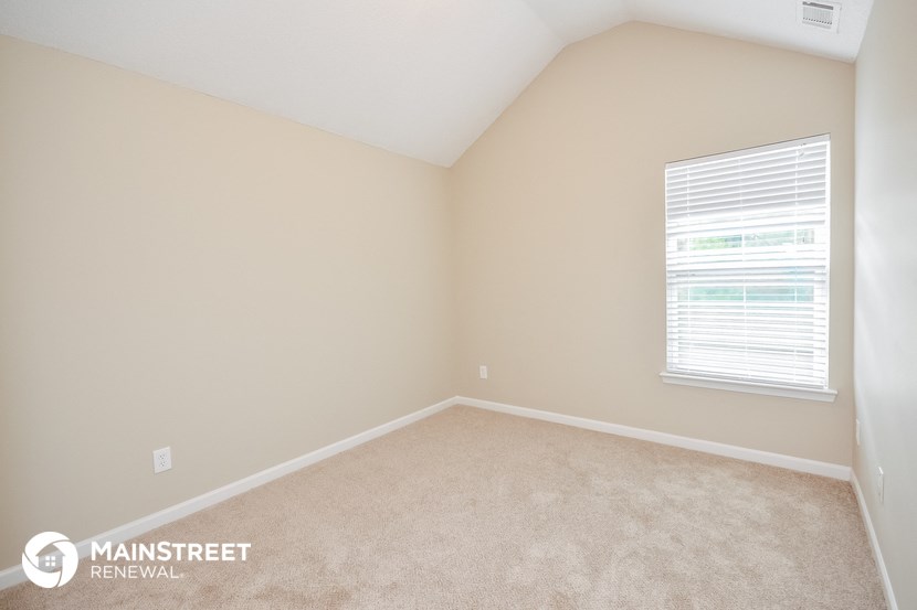 the upstairs bedroom with beige carpet and a window