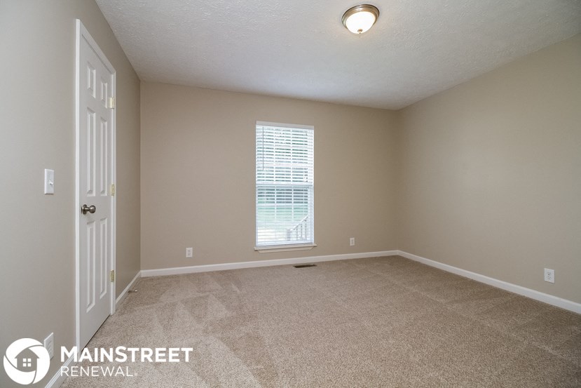 the spacious living room in this manufactured home has carpeted flooring and a window