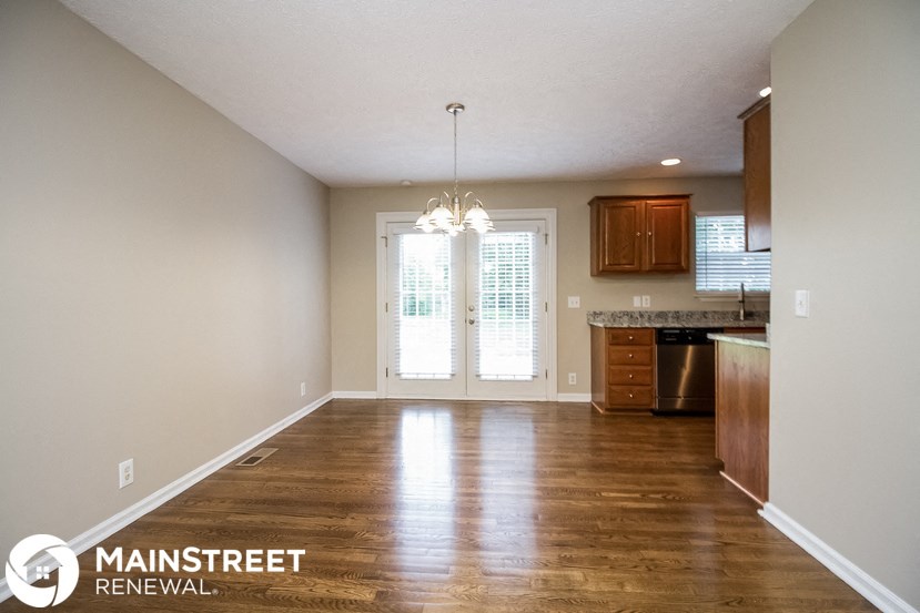 an empty living room with wood floors and a kitchen