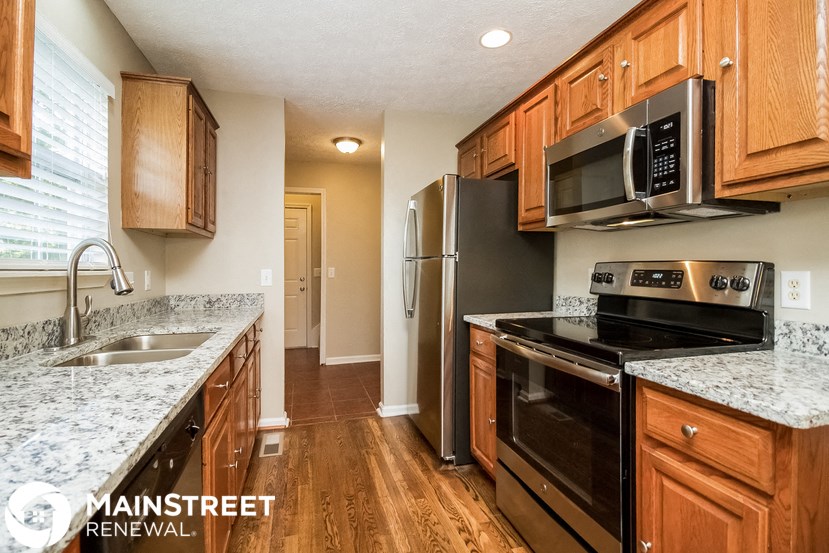 a kitchen with wood cabinets and black appliances and granite counter tops