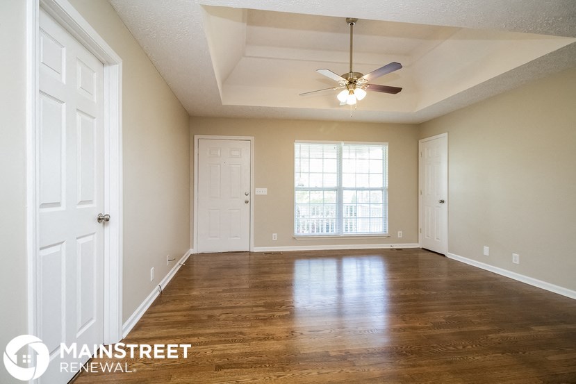 an empty living room with a ceiling fan and a window
