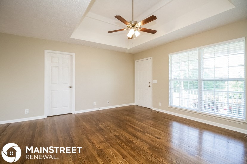 a living room with wood floors and a ceiling fan