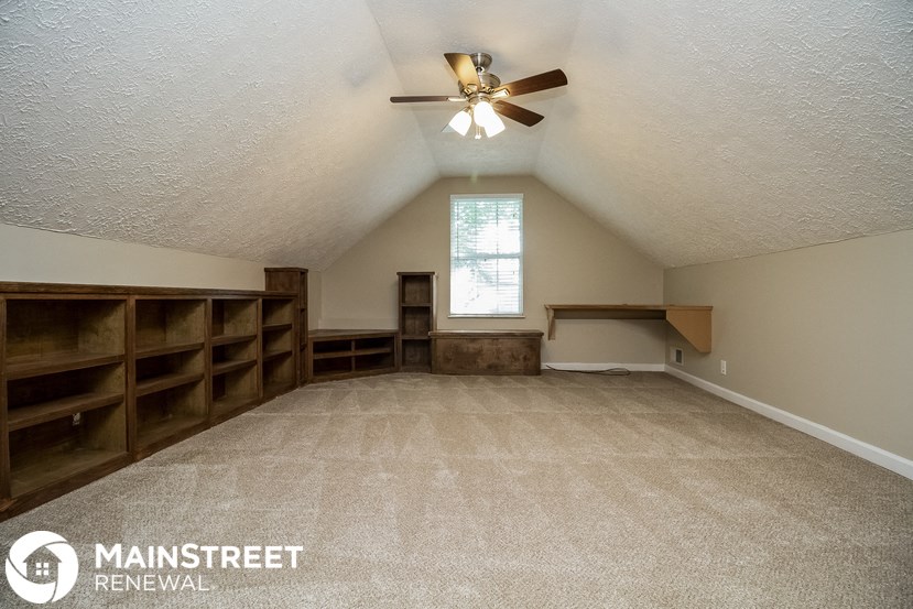 the bonus room has built in bookshelves and a ceiling fan