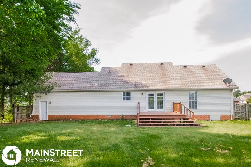 the front of a white house with a porch and a tree