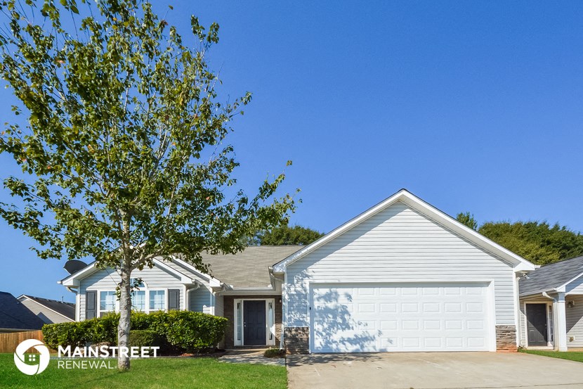 a white house with a white garage door and a tree