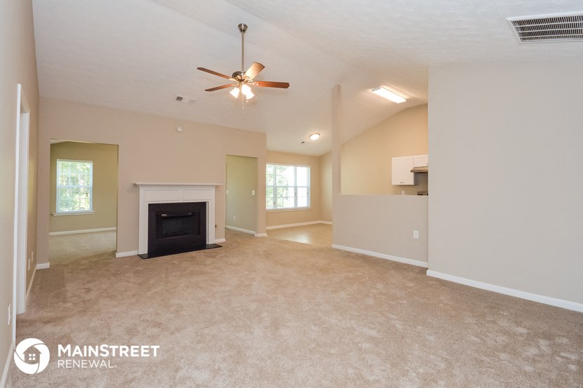 the spacious living room with fireplace and ceiling fan