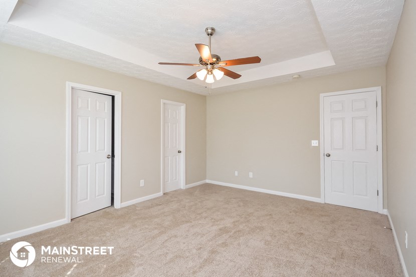 a living room with two doors and a ceiling fan