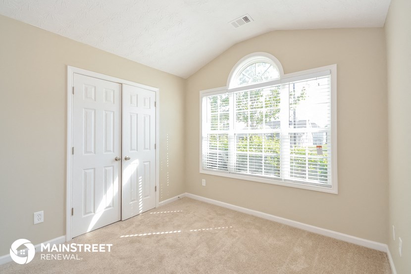 the master bedroom has a large window and carpeted flooring
