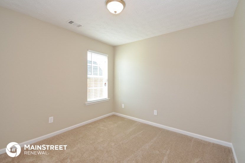 the upstairs bedroom with carpet and a window