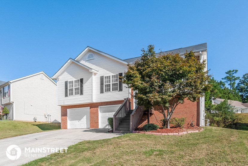 a white house with a staircase and a tree in front of it