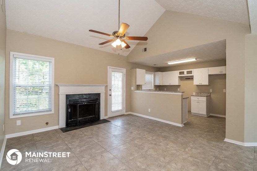 an empty living room with a fireplace and a ceiling fan