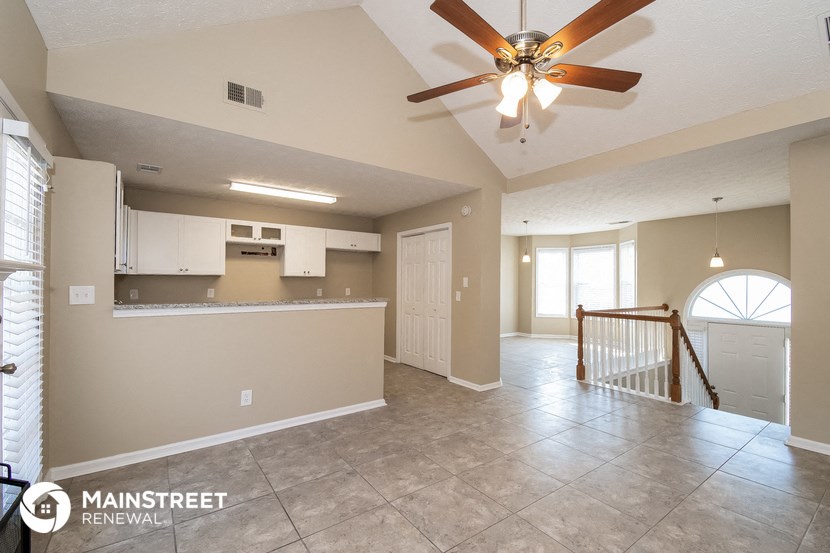an empty living room and kitchen with a ceiling fan