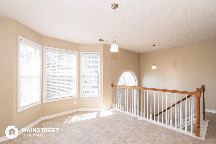 the upstairs landing of a home with a staircase and large windows