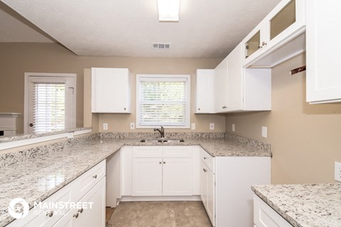 a white kitchen with white cabinets and granite counter tops