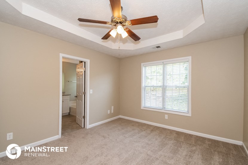 the master bedroom has a ceiling fan and a door to the bathroom