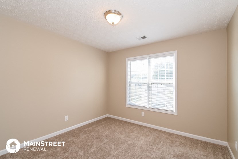 a bedroom with a window and a carpeted floor