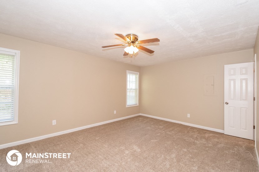 the master bedroom has a ceiling fan and a carpeted floor