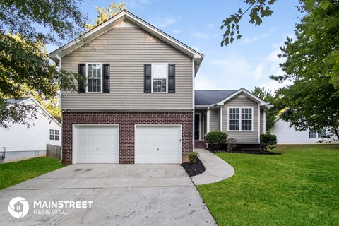 a house with two garage doors in front of a lawn