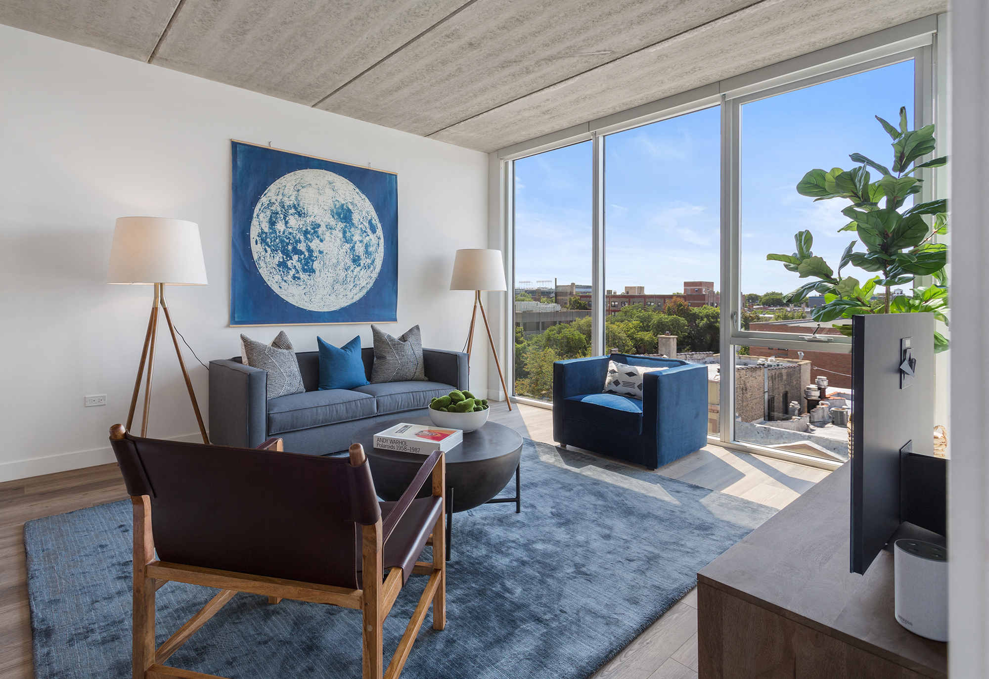 A living room with a blue rug and a large window.