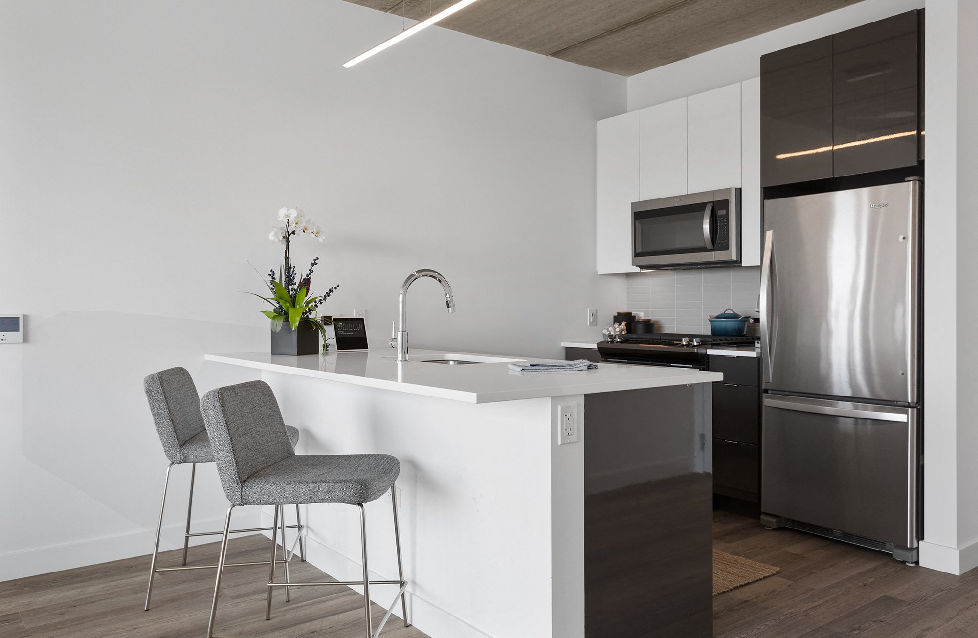 A modern kitchen with a grey chair and a white counter.