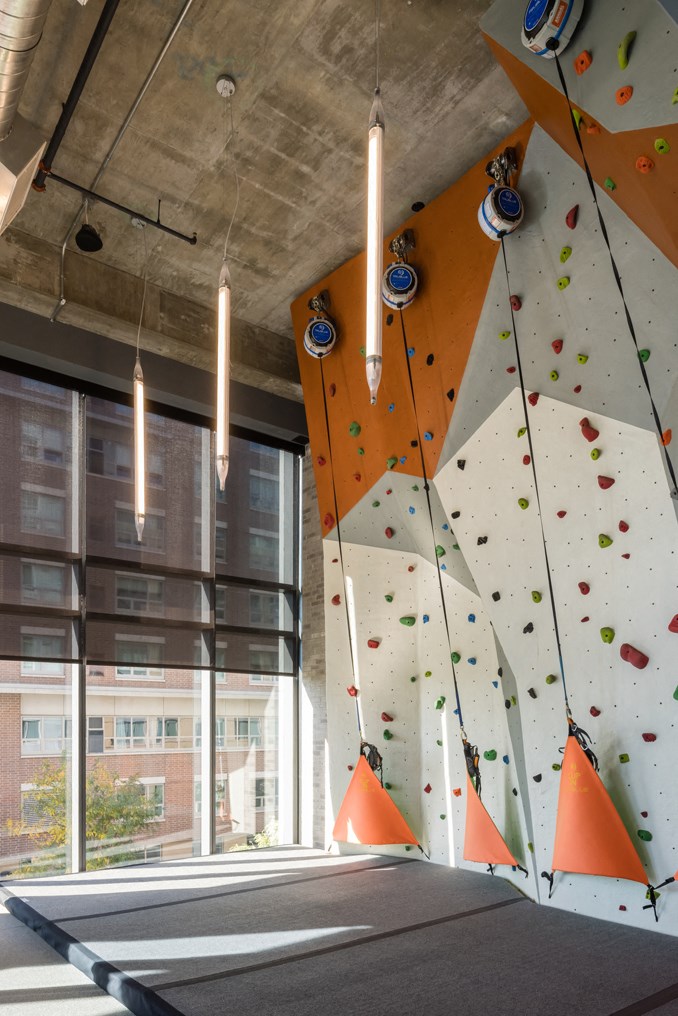 a climbing wall in the lobby of a building with large windows