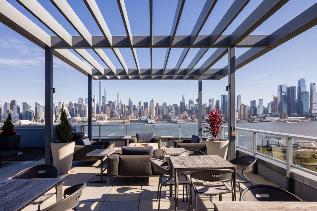 a roof top patio with tables and chairs and a view of the city