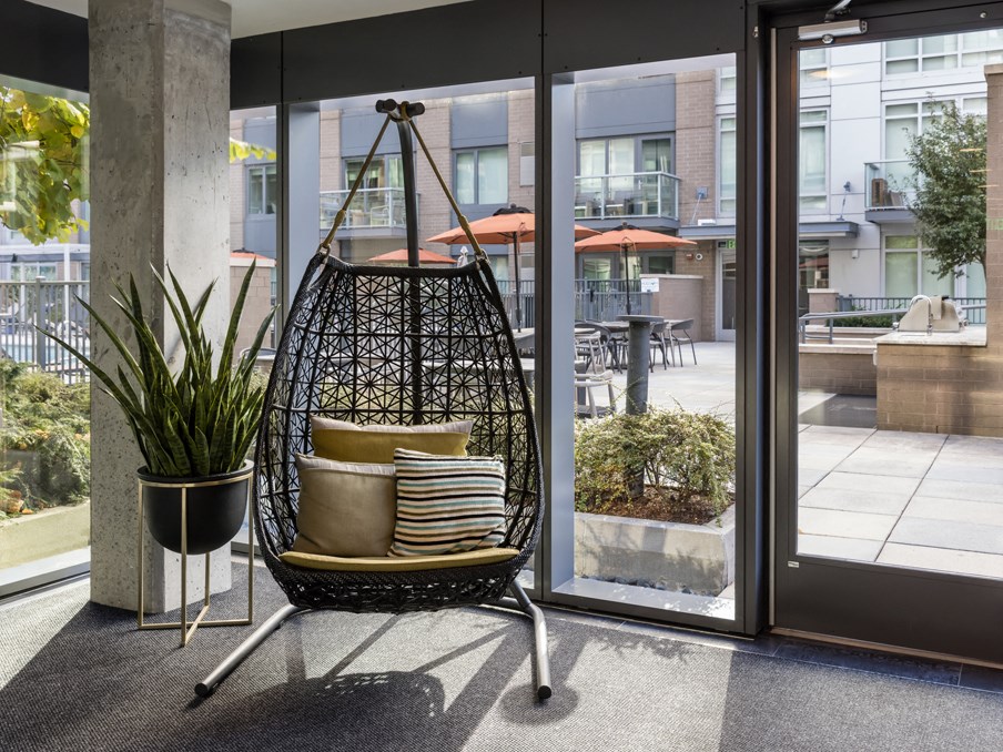a swinging chair with pillows on it in front of a window