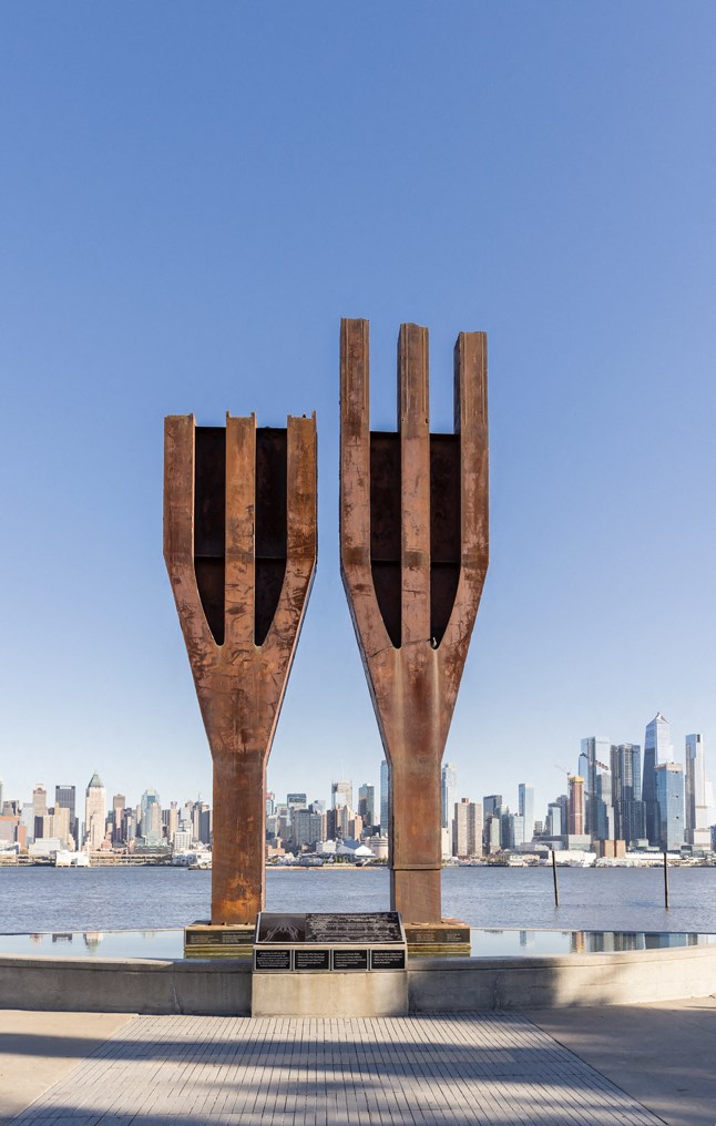a sculpture of twoowers with a city skyline in the background