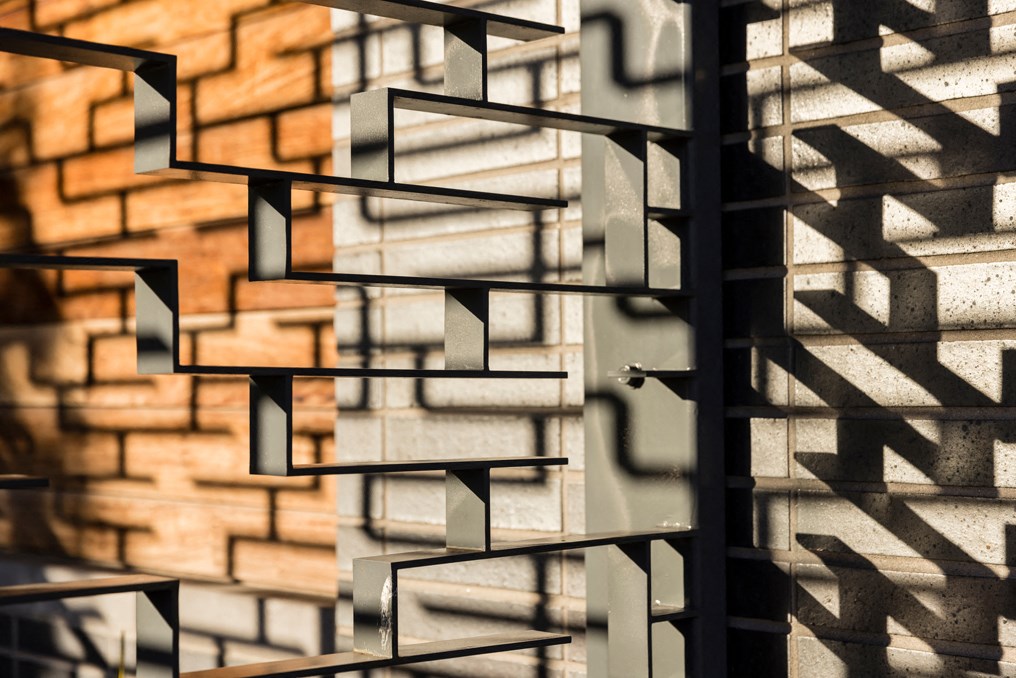 a brick wall with shadows on it and a metal railing