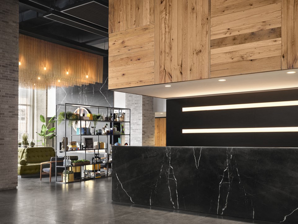 a black marble reception desk in a lobby with a wood ceiling