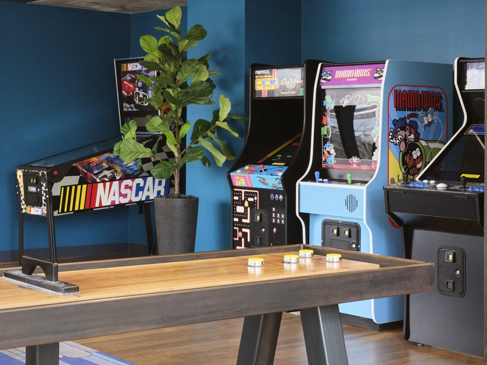 a room with a wooden table and two arcade games