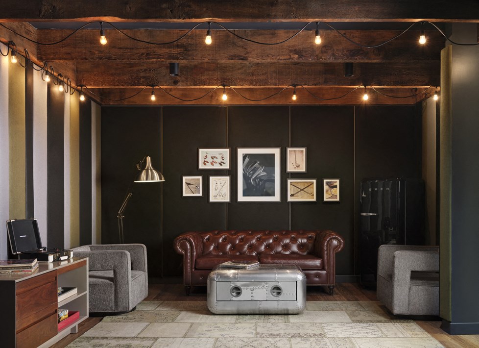 a living room with a leather couch and some lights on the ceiling