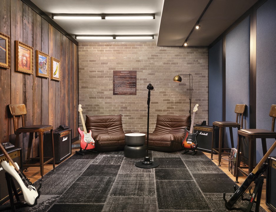 a music room with guitars and couches and a brick wall