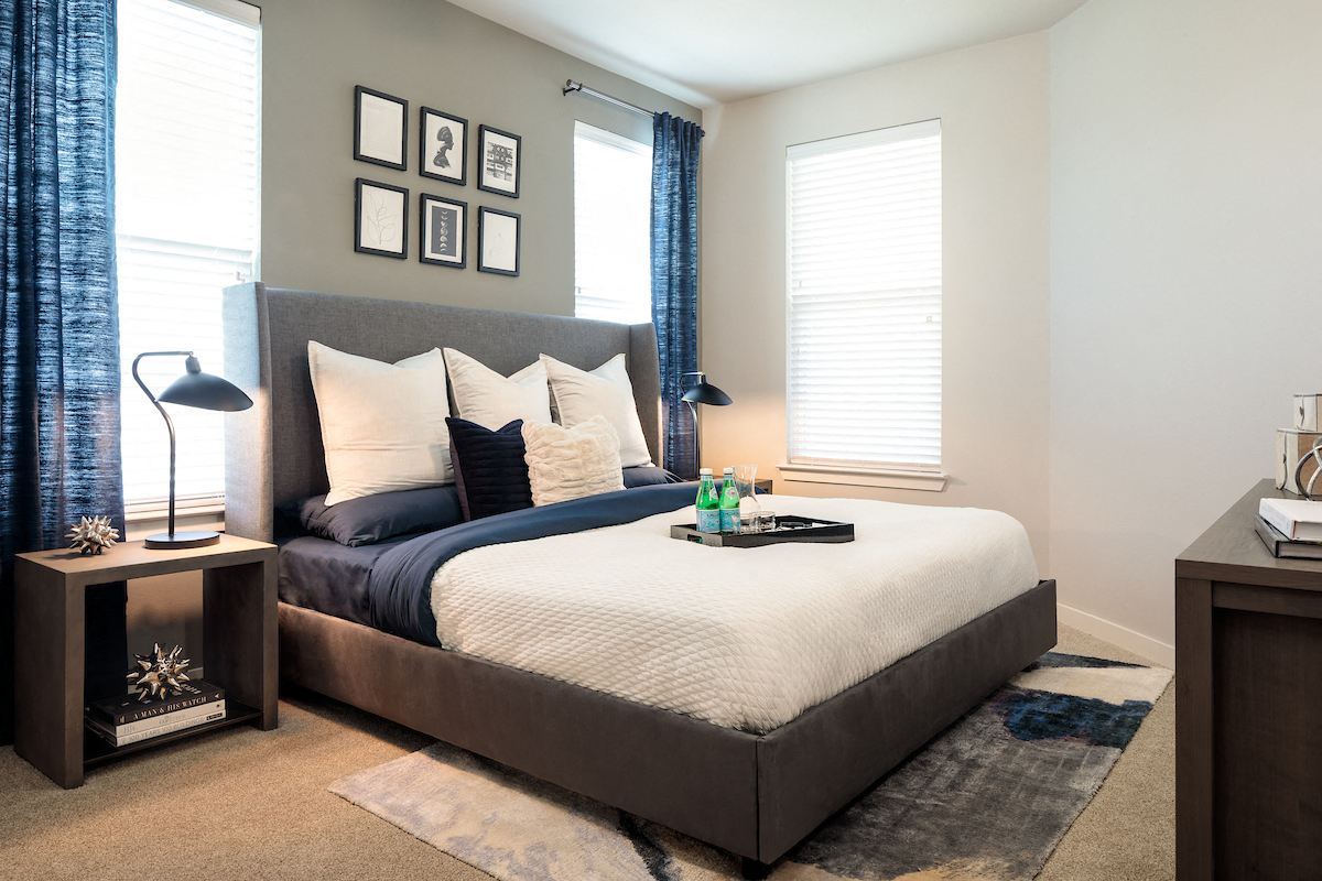 A bedroom with a large bed and a nightstand with a lamp.