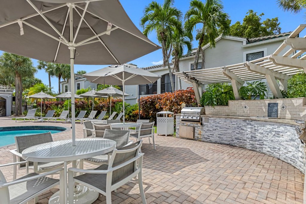 a patio with tables and umbrellas next to a swimming pool