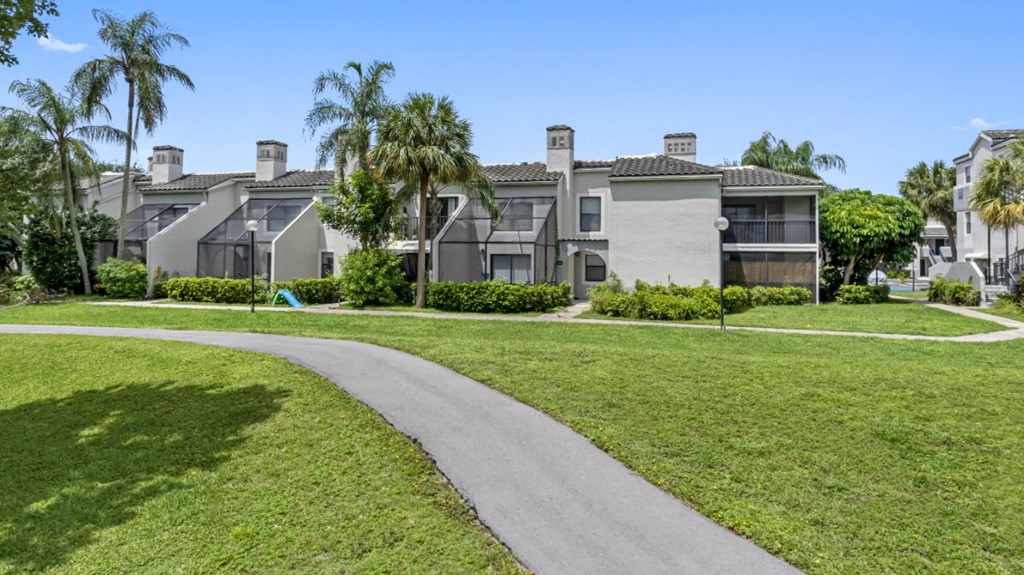a sidewalk leading to a row of houses with palm trees