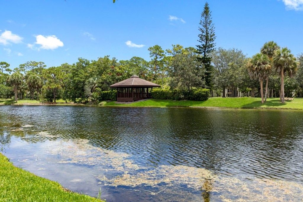 a gazebo on the shore of a lake in a park