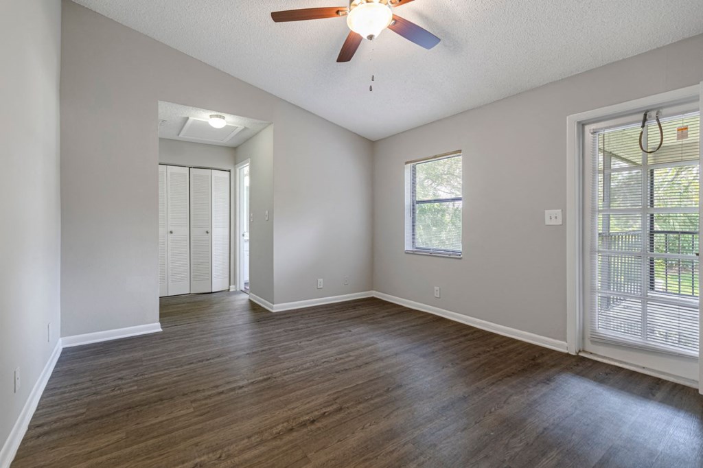 an empty living room with wood floors and a ceiling fan